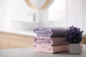 Stack of fresh towels on table in bathroom. 